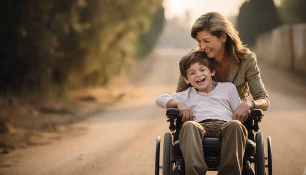 Una madre camina con su hijo en silla de ruedas por un camino al atardecer
